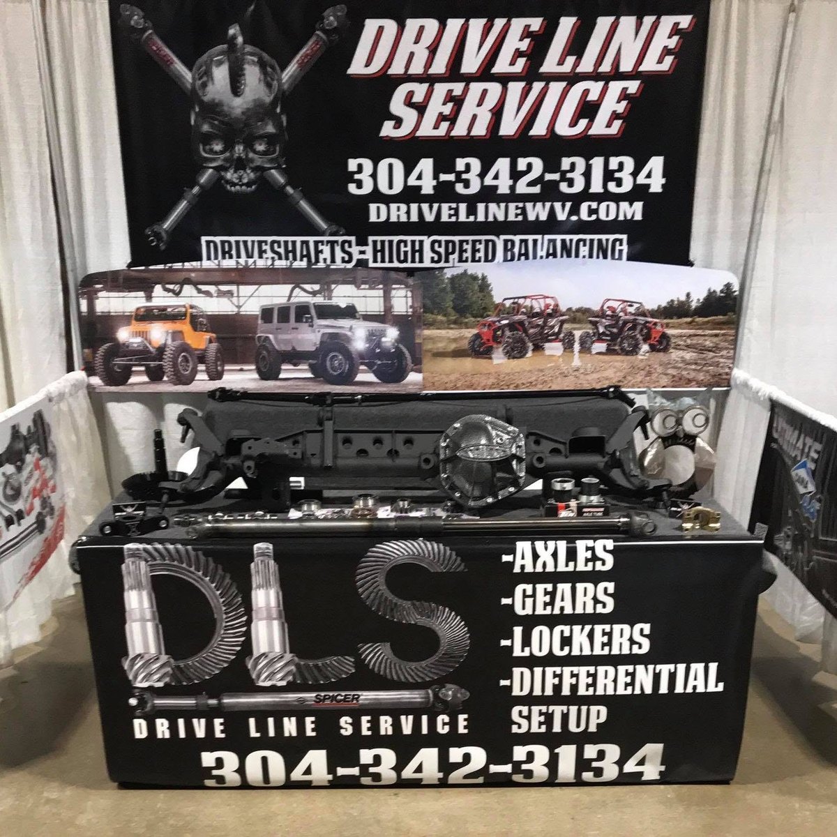 Drive Line Service trade show display with axle assemblies, driveshafts and a differential on the table